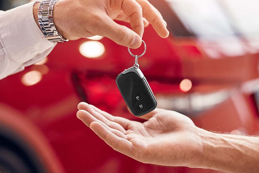 A sales agent hanging over a car key to a customer